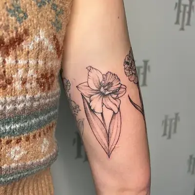 Fine line tattoo of floral daffodil with minimalist shading on the bicep by Ruby Gore, fine line tattoo artist portland