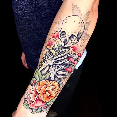 Forearm tattoo featuring a skull and vibrant flowers by Ruby Gore, nature tattoo artist portland