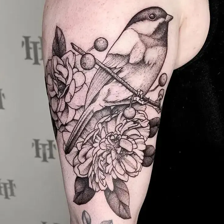 Fine line tattoo of a chickadee bird on arm, minimalist style with botanical elements