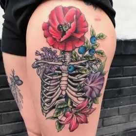 Colorful skeleton ribcage tattoo with red poppy and blueberries featuring anatomical detail by floral tattoo artist Ruby Gore in Portland