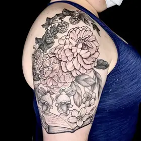 Black and gray dahlia tattoo on upper arm featuring detailed shading with acorns and botanical elements by floral tattoo artist Ruby Gore in Portland
