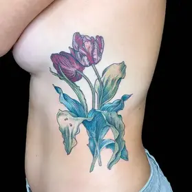 Colorful tulip tattoo on ribcage featuring purple and pink flowers with blue-green leaves by floral tattoo artist Ruby Gore in Portland