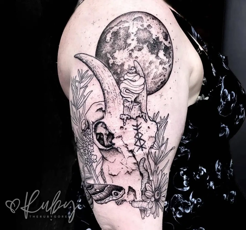 Shoulder scar cover up tattoo with a skull, botanical accents, and a detailed moon, blending natural and mystical witchy elements to hide scars.