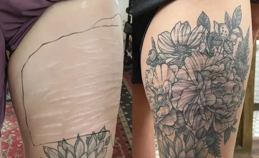Black and gray botanical thigh tattoo scar cover up featuring detailed flowers and leaves by scar cover up tattoo artist Ruby Gore in Portland